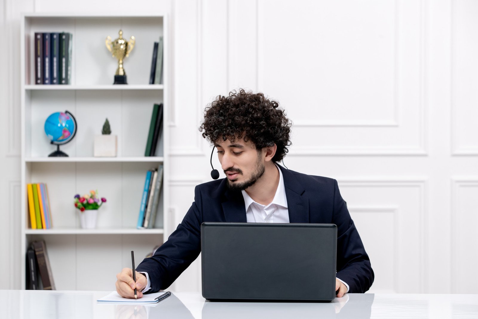 customer-service-cute-brunette-guy-office-suit-with-computer-headset-writing-notes